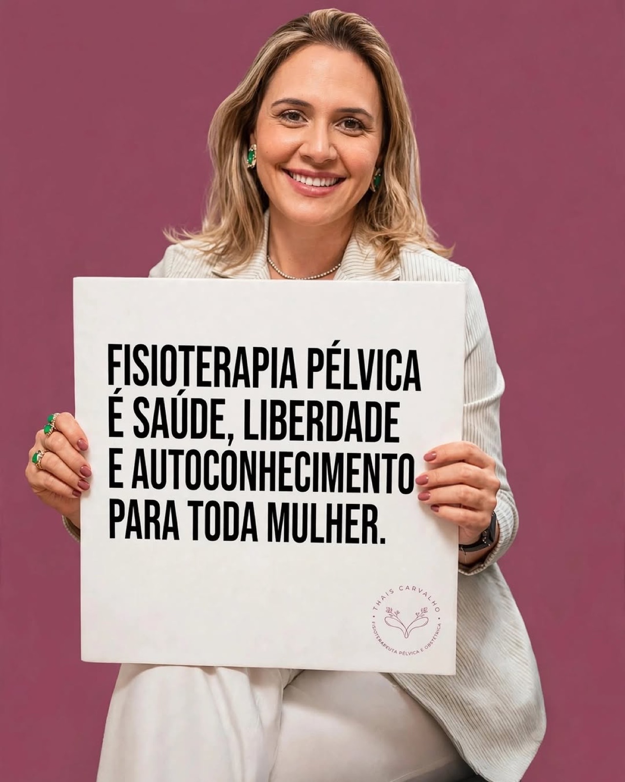 Thais Carvalho, fisioterapeuta pélvica, sorrindo e segurando uma placa com a frase: fisioterapia pélvica é saúde, liberdade e autoconhecimento para toda mulher